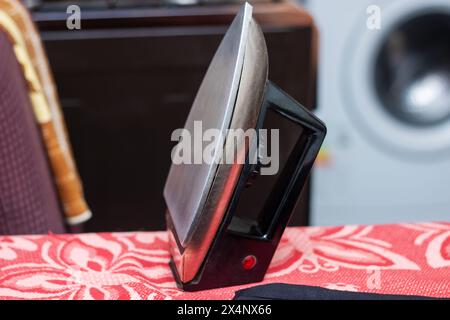Auf einer roten Tischdecke steht ein schwarzes Eisen, das das Automobil-Design repräsentiert, neben Holz, das Autoteile in einem stilvollen Ambiente darstellt Stockfoto