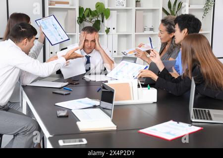 Reifer Geschäftsmann, der unter lauten Kollegen im Büro leidet Stockfoto