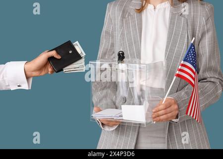 Hand, die Geldbörse mit Geld in die Wahlbox auf blauem Hintergrund legt. Wahlkonzept Stockfoto