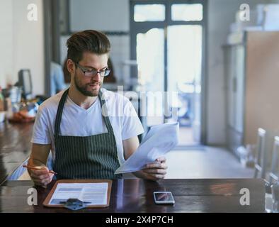 Barista, Arbeits- und Café-Shop mit Papierkram, Bestellung und Bestandsaufnahme oder Schreiben, Café und männlicher Manager. Kleine Unternehmen, Unternehmer und Checkliste oder Stockfoto