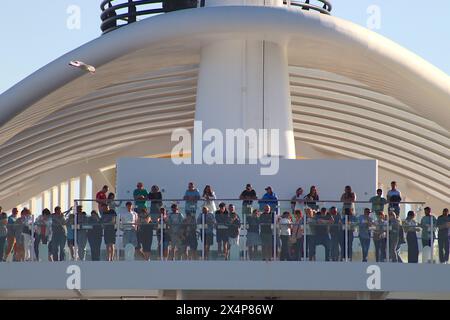Kreuzfahrtpassagiere an Bord des Exzellenz-Kreuzfahrtschiffs Costa Smeralda säumen die Decks, während sich das Schiff auf die Abfahrt ihres Liegeplatzes in Barcelona, 2024, vorbereitet. Stockfoto