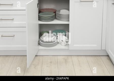 Reinigen Sie Teller und anderes Geschirr auf den Regalen im Schrank im Innenbereich Stockfoto