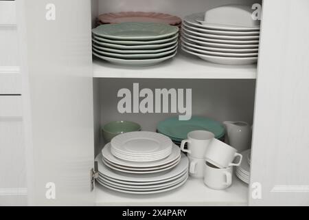 Reinigen Sie Teller und anderes Geschirr auf den Regalen im Schrank im Innenbereich Stockfoto