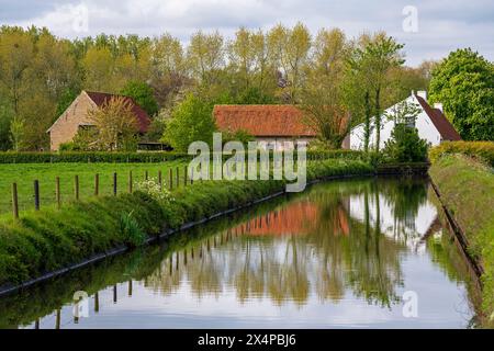 Traditionelle ländliche flämische Architektur mit Kanal, Stadt Moere, Region Brügge, Flandern, Belgien. Stockfoto