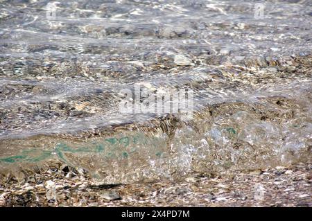 Erleben Sie die faszinierende Schönheit des kristallklaren Wassers, das sanft entlang einer felsigen Küste plätschert. Dieses fesselnde Bild fängt die ruhige Harmonie ein Stockfoto