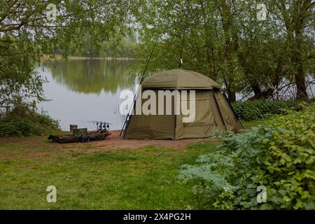 Landschaftsbild eines Sees und umliegender Bäume mit einem Fischerheim und Ausrüstung im Vorderboden. Stockfoto