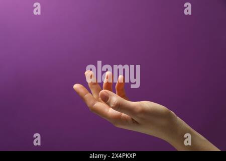 Frau, die etwas in der Hand hält, auf violettem Hintergrund, Nahaufnahme. Leerzeichen für Text Stockfoto