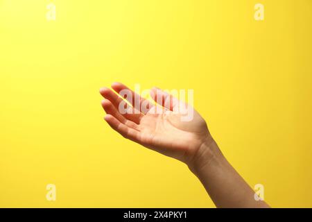 Frau, die etwas in der Hand hält auf gelbem Hintergrund, Nahaufnahme Stockfoto