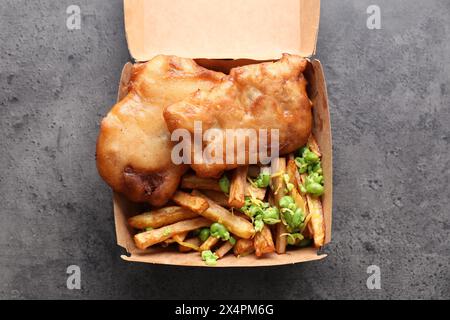 Leckerer Fisch, Chips und Erbsen in Papierkarton auf grauem Tisch, Draufsicht Stockfoto