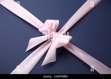 Rosa Satinband mit Schleife auf blauem Hintergrund Stockfoto