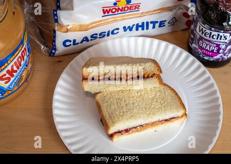 Ein Sandwich mit Erdnussbutter und Gelee auf Wunderbrot, das in zwei Hälften geschnitten wird, ist ein Kultstück für die Kindheit zum Mittagessen, 2024, USA Stockfoto