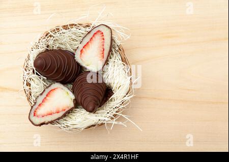 Osterei gefüllt mit Erdbeere und geriebener Kokosnuss in Aussicht von oben isoliert auf hölzernem Hintergrund. Stockfoto