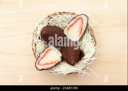 Osterei gefüllt mit Erdbeere und geriebener Kokosnuss in Aussicht von oben isoliert auf hölzernem Hintergrund. Stockfoto