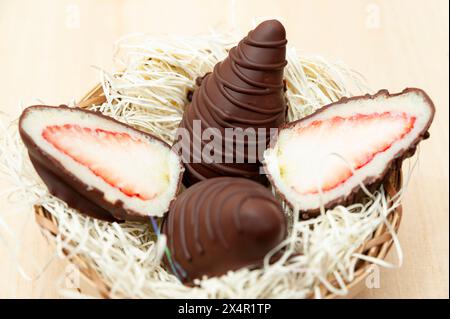 Osterei gefüllt mit Erdbeere und geriebener Kokosnuss in Aussicht von oben isoliert auf hölzernem Hintergrund. Stockfoto