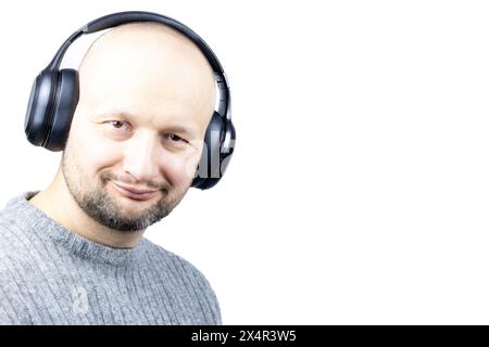 Das ist ein fesselndes Porträt eines Mannes, vor einem weißen Hintergrund. Er trägt einen fein gestrickten grauen Wollpullover, dessen Gesicht Freude ausdrückt Stockfoto