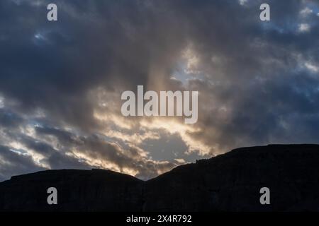 Dramatische Sonnenstrahlen brechen bei Sonnenuntergang durch die Gewitterwolken Stockfoto