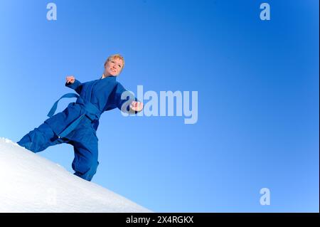 Junge Frau in blauem Kimono steht auf Schnee und bereit zum Kampf Stockfoto