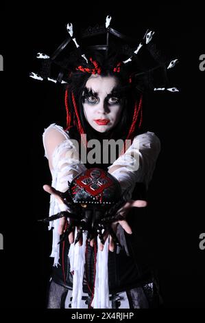 Porträt einer Frau mit Voodoo-Schamanen-Make-up-Hold-Spielzeugspinne isoliert auf Schwarz Stockfoto