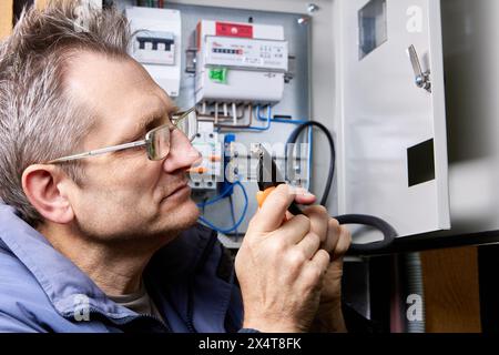 Schneiden Sie die Ummantelung des Stromkabels mit einem einziehbaren Universalmesser ab, und schneiden Sie die äußere Ummantelung des Hochspannungskabels ab. Stockfoto