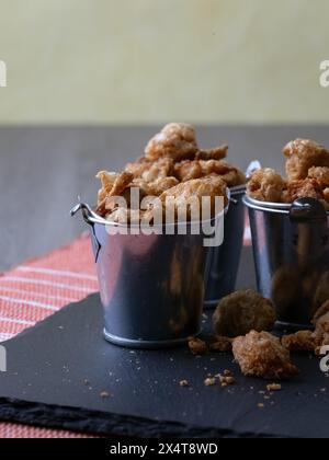 Snack mit gesalzenen Schweineschalen in Minieimern Stockfoto