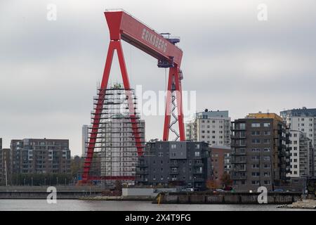 Göteborg, Schweden - Oktober 30 2021: Kran im Hafenbereich mit Gerüsten, umgeben von Wohnhäusern. Bauarbeiter sichtbar auf Gerüsten Stockfoto