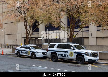 Washington DC, USA - 14. November 2021: FBI-Polizeiautos parkten auf der Straße unter zwei Bäumen. Betongebäude im Hintergrund. Keine sichtbaren Personen Stockfoto