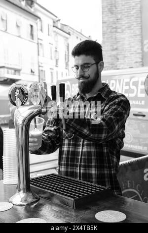 Junger Barkeeper, der Bier auf der Dorfparty gießt Stockfoto