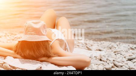 Nicht erkennbare positive Frau in weißem Bikini, die im Sommer am Strand am Meer sonnt oder gebräunt ist. Zeitlupe des glücklichen Touristen, der Sonnenbräune genießt Stockfoto