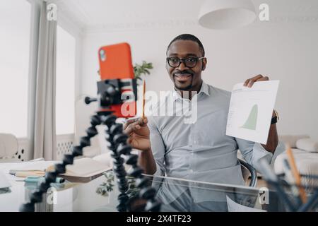 Selbstbewusster Geschäftsmann, der Finanzdaten präsentiert, während er für einen professionellen Vlog aufzeichnet. Stockfoto