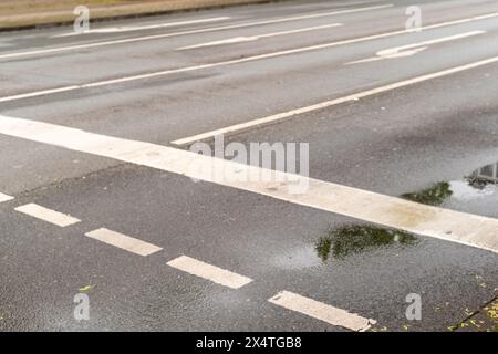 Richtungspfeile auf einer nassen Asphaltstraße Stockfoto