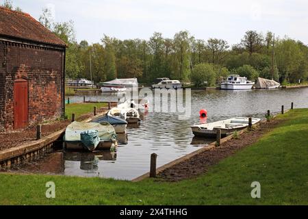 Kleine Boote, die im Frühjahr in der Pennygate Staithe an den Norfolk Broads in Barton Turf, Norfolk, England, Großbritannien, ankerten. Stockfoto