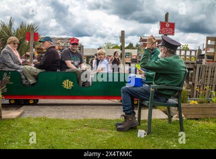 Ein Freiwilliger Wächter winkt den Passagieren auf der Eisenbahnmission Miniatur-Dampflokomotive und Wagen der South Downs Light Railway, Pulborough, Großbritannien Stockfoto