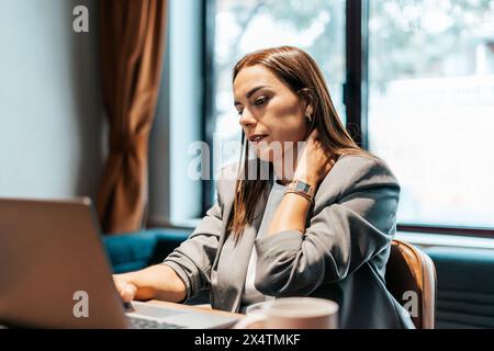 Müde Geschäftsfrau, die in einem Büro vor dem Laptop sitzt Stockfoto