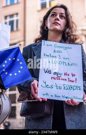 Eine Demonstrantin hält ein Plakat, das für engere Beziehungen zwischen Georgien und der Europäischen Union plädiert, und neben ihr befindet sich eine EU-Flagge. Am 30. April 2024 protestierte eine kleine Gruppe georgischer Bewohner Warschaus gegen den neuen Gesetzesentwurf, der dem georgischen parlament vorgelegt wurde. Das Gesetz würde Nichtregierungsorganisationen und andere gemeinnützige Organisationen zwingen, sich als „die Interessen einer ausländischen Macht verfolgen“ zu registrieren, wenn sie mehr als 20 % der Mittel aus ausländischen Quellen erhalten. Das Gesetz wird als "das russische Gesetz" angeprangert, da die Regierung Wladimir Putins ein ähnliches Gesetz benutzt, um Medien und andere Organisationen cri zu hemmen Stockfoto