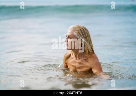 Elderige Frau in gutem Zustand, die im Meer baden. Stockfoto