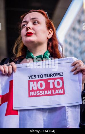 Warschau, Mazowieckie, Polen. April 2024 30. Ein Demonstrant hält eine Ecke einer großen georgischen Flagge und ein Plakat mit der Aufschrift „Ja zu Europa! Nein zum russischen Recht während der Demonstration. Am 30. April 2024 protestierte eine kleine Gruppe georgischer Bewohner Warschaus gegen den neuen Gesetzesentwurf, der dem georgischen parlament vorgelegt wurde. Das Gesetz würde Nichtregierungsorganisationen und andere gemeinnützige Organisationen zwingen, sich als "die Interessen einer ausländischen Macht verfolgen" zu registrieren, wenn sie mehr als 20 % der Mittel aus ausländischen Quellen erhalten. Das Gesetz wird als „das russische Gesetz“ angeprangert, da die Regierung von Wladimir Putins ein s verwendet Stockfoto