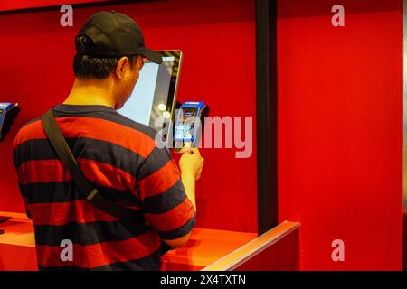 Man Kunde im Geschäft gibt Bestellungen auf und bezahlt per Kreditkarte über den Selbstzahlungskiosk für Fast Food, Zahlungsterminal Stockfoto