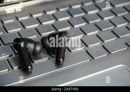 Schwarze schnurlose Ohrhörer auf der Laptop-Tastatur Stockfoto