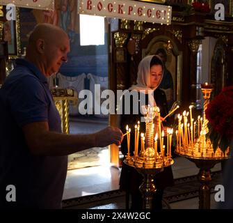 ODESSA, UKRAINE - 5. Mai 2024: Orthodoxe Pfarrer der christlichen Kirche zünden am Tag des Kirchfeiertags Kerzen an der Ikone der Heiligen an Stockfoto