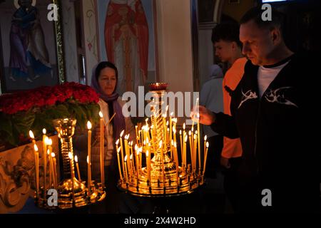 ODESSA, UKRAINE - 5. Mai 2024: Orthodoxe Pfarrer der christlichen Kirche zünden am Tag des Kirchfeiertags Kerzen an der Ikone der Heiligen an Stockfoto