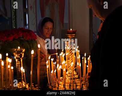 ODESSA, UKRAINE - 5. Mai 2024: Orthodoxe Pfarrer der christlichen Kirche zünden am Tag des Kirchfeiertags Kerzen an der Ikone der Heiligen an Stockfoto