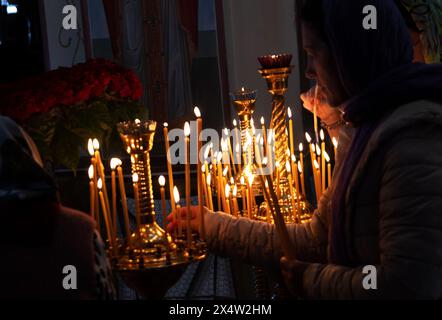 ODESSA, UKRAINE - 5. Mai 2024: Orthodoxe Pfarrer der christlichen Kirche zünden am Tag des Kirchfeiertags Kerzen an der Ikone der Heiligen an Stockfoto