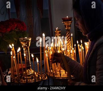 ODESSA, UKRAINE - 5. Mai 2024: Orthodoxe Pfarrer der christlichen Kirche zünden am Tag des Kirchfeiertags Kerzen an der Ikone der Heiligen an Stockfoto