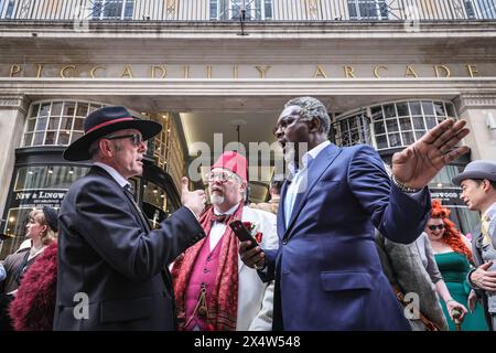 London, Großbritannien. Mai 2024. Gustav Temple, Organisator und Redakteur des Magazins „The CHAP“ (links), spricht über die Route. Am jährlichen Grand Flaneur Walk nehmen eine Gruppe von elegant gekleideten Jungs, Kapellen und Tänzerinnen Teil, die neben der Statue von Beau Brummell in der Jermyn Street beginnen und dann durch die Londoner St. James' Gegend schlendern. Quelle: Imageplotter/Alamy Live News Stockfoto