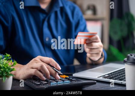 Person, die Ausgaben mit Rechner und Kreditkarte berechnet, indikativ für das persönliche Finanzmanagement Stockfoto