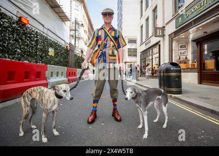 London, Großbritannien. 5. Mai 2024. Ein elegant gekleideter Mann mit seinen Hunden nimmt am vierten Grand flâneur Walk Teil. Beginnend an der Beau Brummell Statue in der Jermyn Street fällt der Spaziergang mit dem 25. Jahrestag des CHAP Magazins zusammen und wird definiert als ein Spaziergang ohne Zweck, der die Kunst des flâneur feiert, ohne irgendwohin zu gehen, und ein Gegenmittel für die Anforderungen des modernen Lebens und des digitalen Smartphones. Quelle: Stephen Chung / Alamy Live News Stockfoto