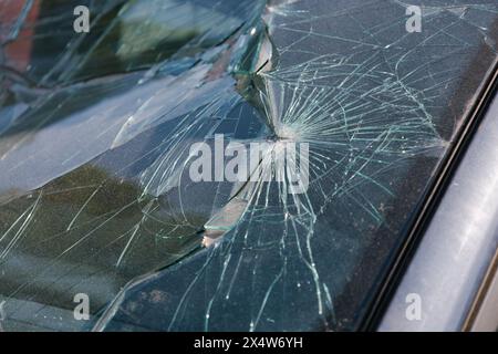 Defekte Windschutzscheibe des Autos. Glasbruch. Dellen an der Windschutzscheibe nach einem Kollisionsunfall. Beschädigtes Fahrzeug auf der Straße. Stockfoto