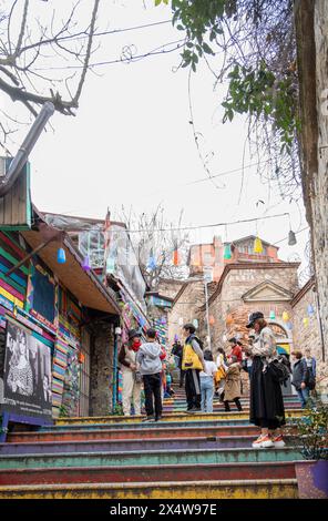 Farbenfrohes Foto von Touristen, die auf historischen Treppen in Istanbuls berühmtem Balat-Viertel spazieren, umgeben von lebendiger Architektur und reicher kultureller Herita Stockfoto