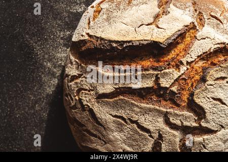 Nahaufnahme eines knusprigen Sauerteigbrotes mit strukturierter Kruste auf dunklem Hintergrund Stockfoto
