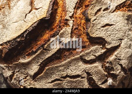 Extreme Nahaufnahme einer Sauerteigbrotkruste mit detaillierter Textur und Rissen Stockfoto